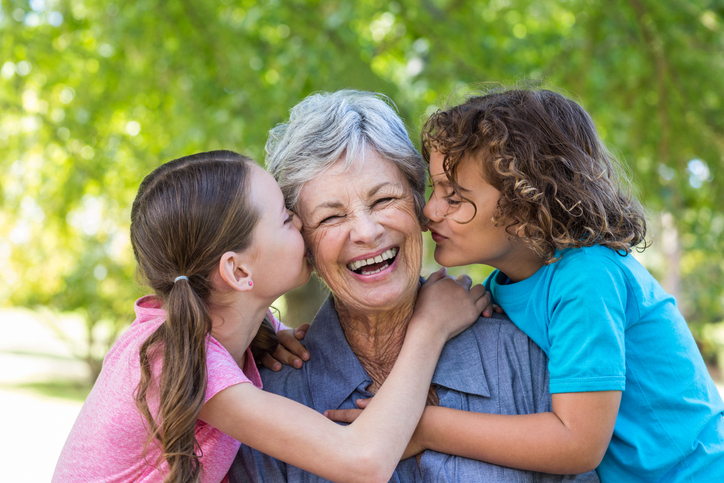extended family smiling and kissing in a park